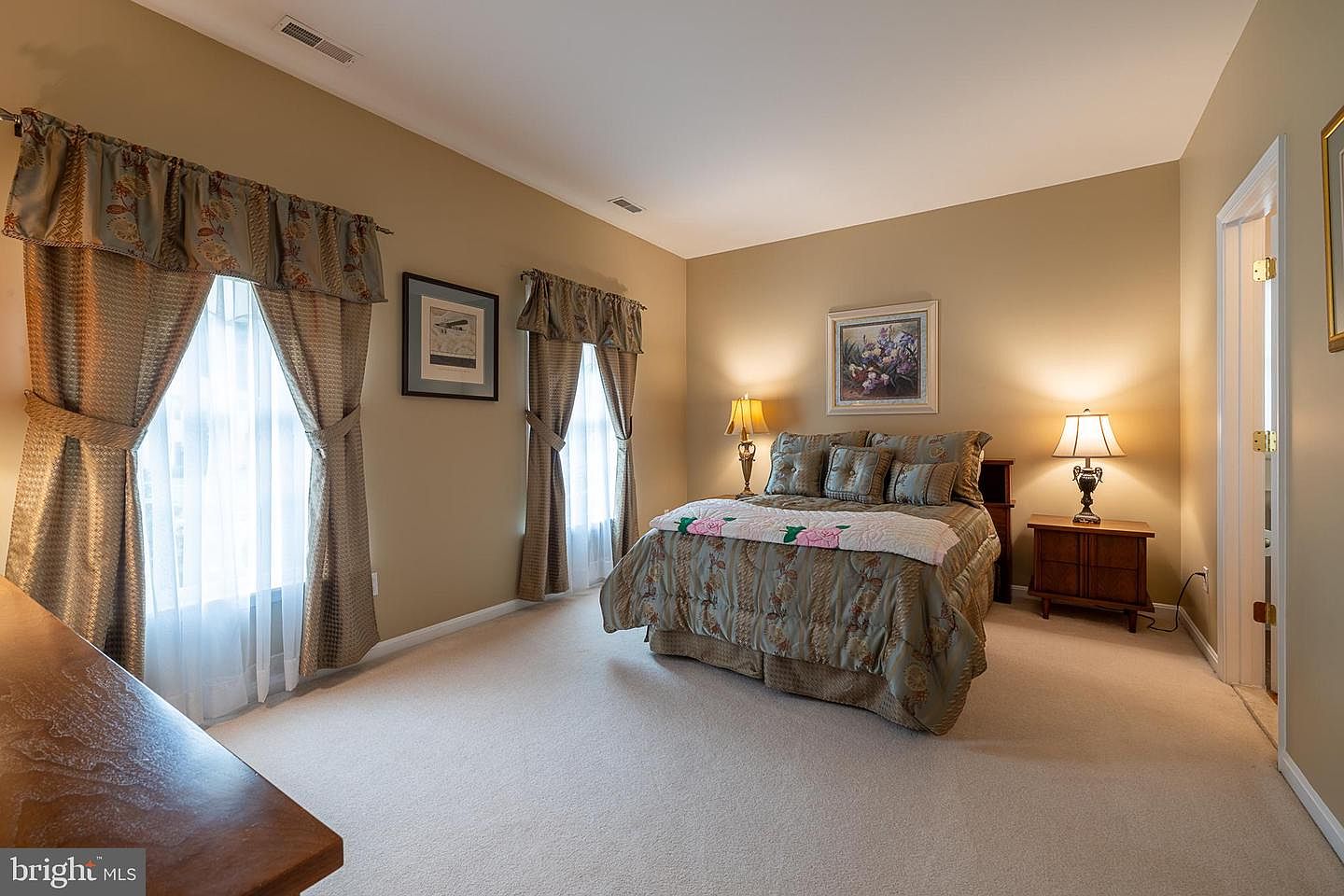 Bedroom with vaulted ceiling and twin curtained windows