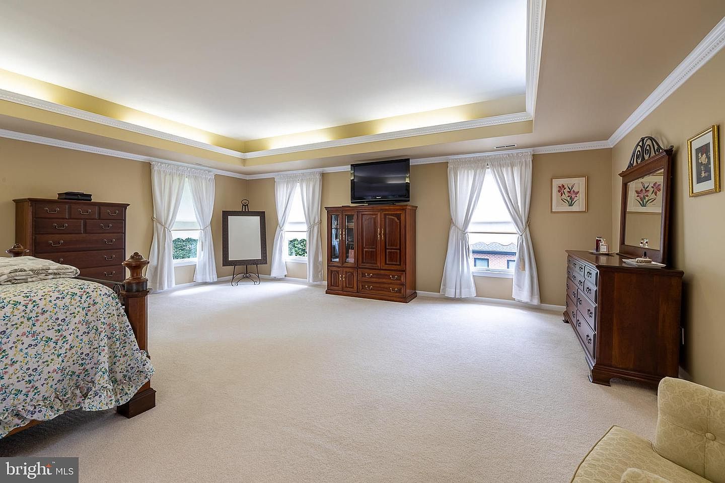 Primary bedroom with lighted tray ceiling and bay window