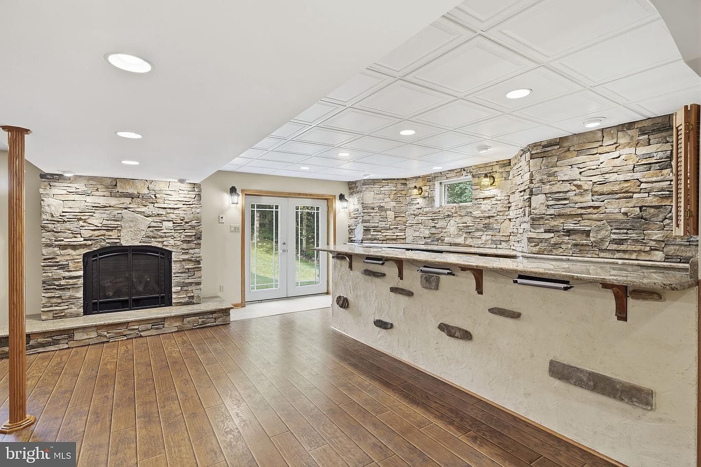 Lower-level recreation room with a stone-faced wet bar and gas fireplace